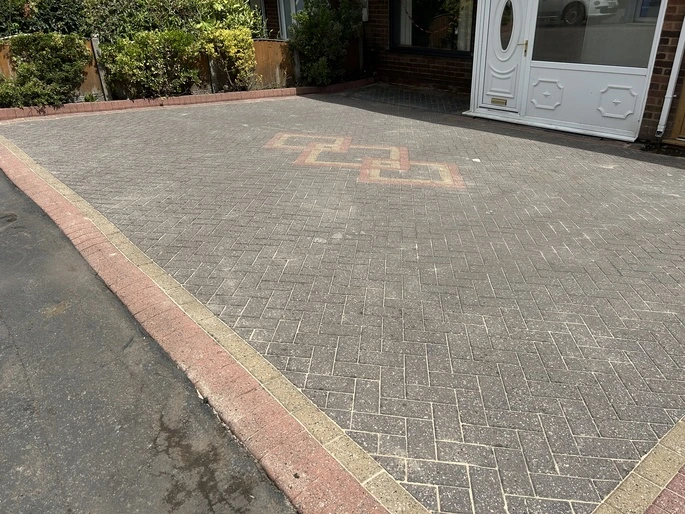 Clean, freshly sanded block paving driveway showing restored red pattern borders in Dudley.
