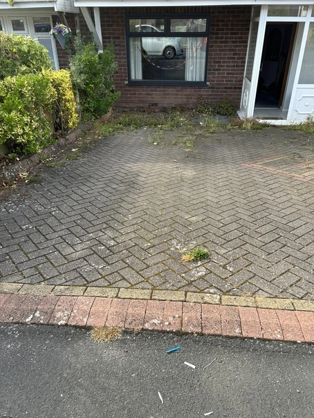 Block paving driveway heavily overrun with weeds in Dudley before deep pressure cleaning.